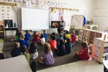 Classroom of children sitting on the floor listening to their teacher