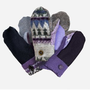 Three pairs of handmade mittens on top of each other. One black and purple pair. One Grey with tree patterned pair, and one two tone purple pair.